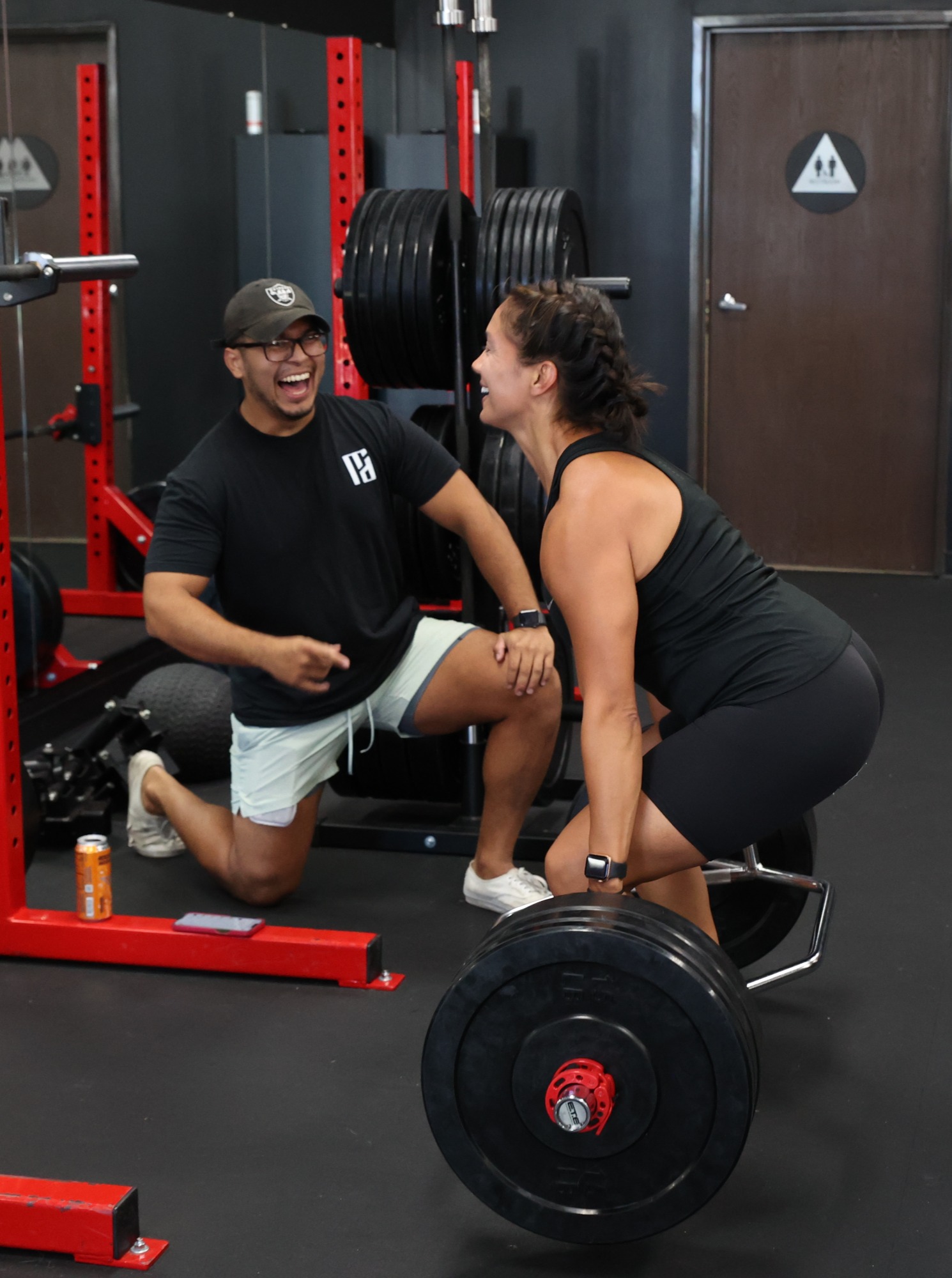 Train With Dave coach and client sharing a laugh during a deadlift session at the Orange studio